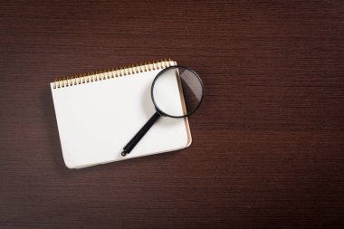 defter ve ahşap arka plan üzerinde büyüteç