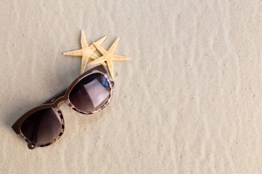 Yığın kabukları ve kum üzerinde yalan güneş gözlüğü 