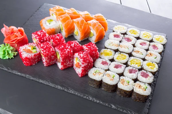 Japanese restaurant, sushi rolls on black slate plate.