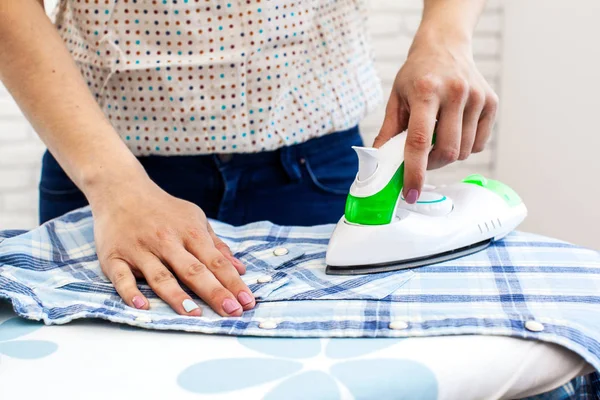 Closeup of woman ironing clothes on ironing board