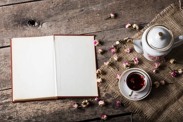 Books, flowers and cup of tea on wooden table with sackcloth