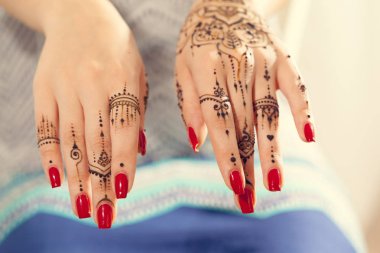 Kırmızı manikürlü eller Mehndi ile 