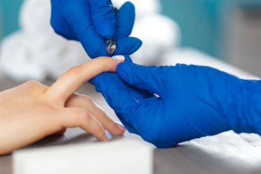 Kadın elleri güzellik salonunda manikür yaptırıyor.