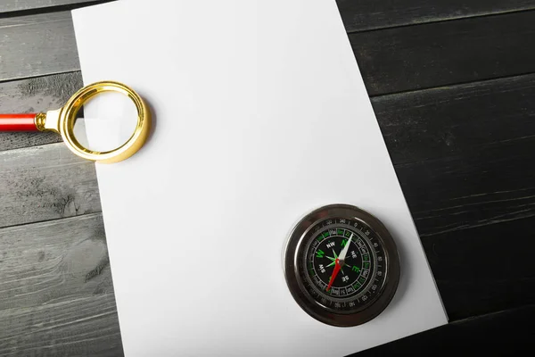 Magnifying glass and blank paper on wooden table
