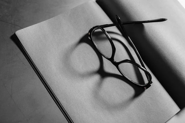 Open notepad with black-rimmed eyeglasses