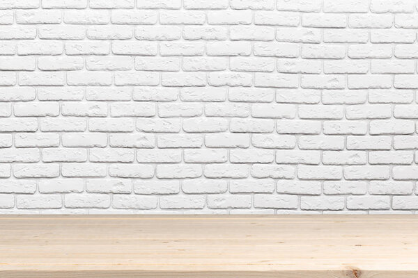Wooden table surface with white brick wall on background