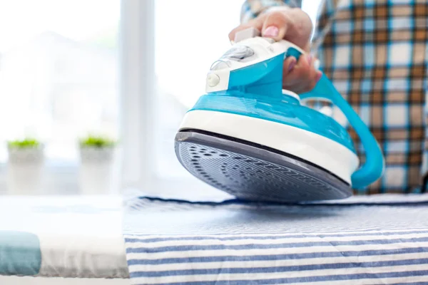 Closeup of woman ironing clothes on ironing board