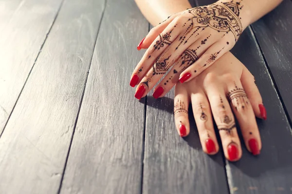 Kırmızı manikürlü eller Mehndi ile 