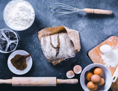 Koyu arka plan boş yemek kitabı, yumurta kabuğu, ekmek, un, oklava ile pişirme. Pişirme için malzemeler.
