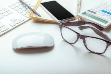 Ofis resepsiyon masası bilgisayar klavye, malzemeleri, hesap makinesi, kalem, gözlük ile 