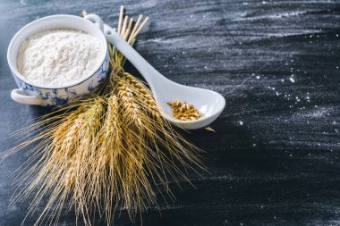 Siyah arka planda buğday kulakları ve un