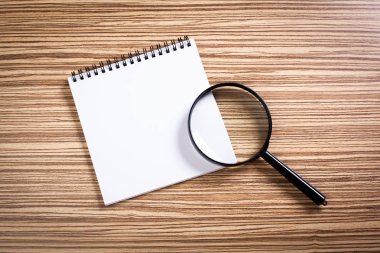defter ve ahşap arka plan üzerinde büyüteç