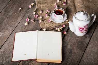 Kitap, çiçekler ve çul ile ahşap tabloda çay