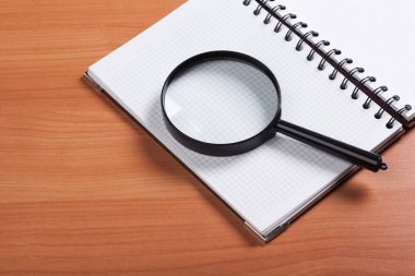 defter ve ahşap arka plan üzerinde büyüteç
