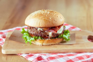 Lezzetli ve iştah açıcı hamburger üzerinde ahşap masa, yakın çekim kesme