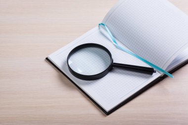 defter ve ahşap arka plan üzerinde büyüteç