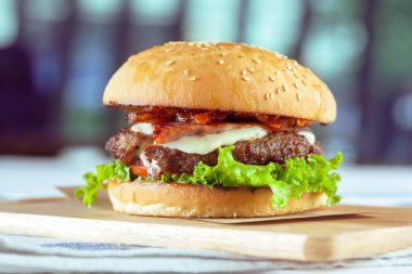 Lezzetli ve iştah açıcı hamburger üzerinde ahşap masa, yakın çekim kesme