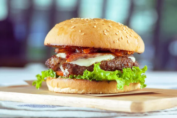 Lezzetli ve iştah açıcı hamburger üzerinde ahşap masa, yakın çekim kesme