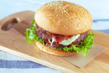 Lezzetli ve iştah açıcı hamburger üzerinde ahşap masa, yakın çekim kesme 