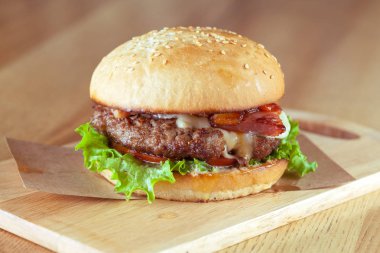 Lezzetli ve iştah açıcı hamburger üzerinde ahşap masa, yakın çekim kesme