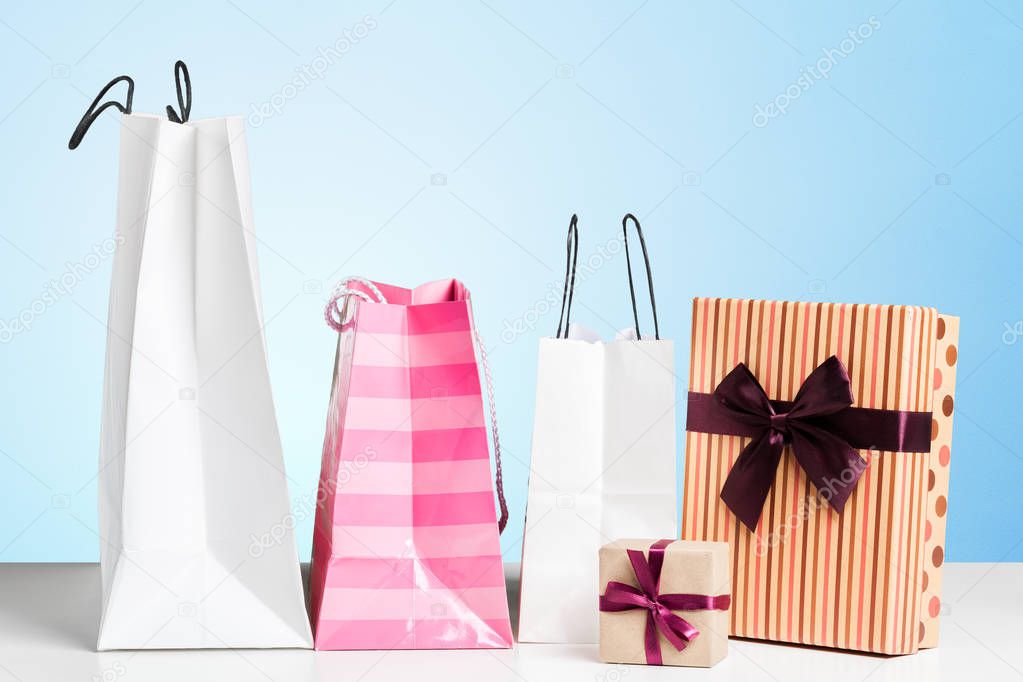 Shopping Bags of presents on white table.