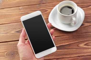 Mobil akıllı telefon ve bir fincan kahve ahşap arka plan doku