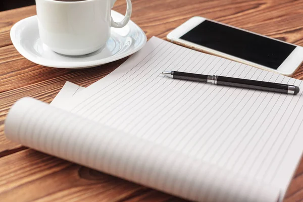 Office desk table top view. Notepad with blank pages on wooden table