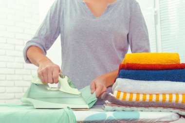 Ütü masasında giysileri ütüleyen bir kadın.