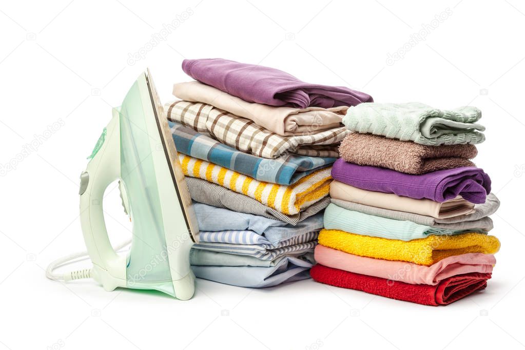 Electric iron and pile of clothes isolated on white background 