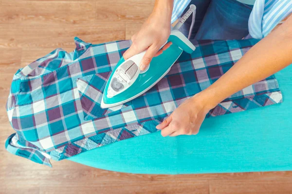 Close-up of woman ironing clothes on ironing board