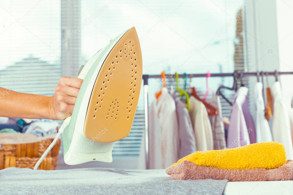 Close-up of woman ironing clothes on ironing board