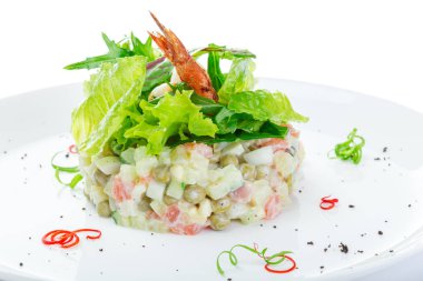 Beyaz bir tabakta tavuk ile Olivier salatası