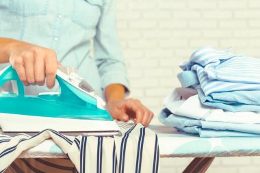 Ütü masasında giysileri ütüleyen bir kadın.