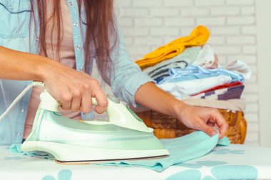 Ütü masasında giysileri ütüleyen bir kadın.