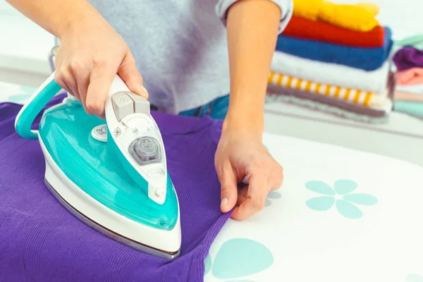 Ütü masasında giysileri ütüleyen bir kadın.