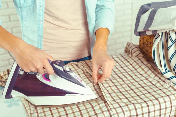 Closeup of woman ironing clothes on ironing board