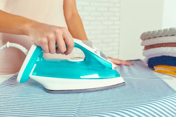 Ütü masasında giysileri ütüleyen bir kadın.