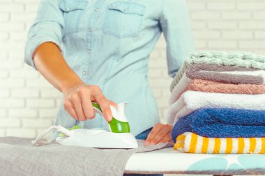 Ütü masasında giysileri ütüleyen bir kadın.