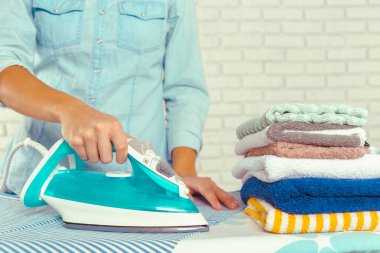 Ütü masasında giysileri ütüleyen bir kadın.