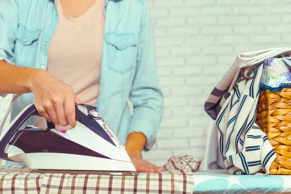 Closeup of woman ironing clothes on ironing board