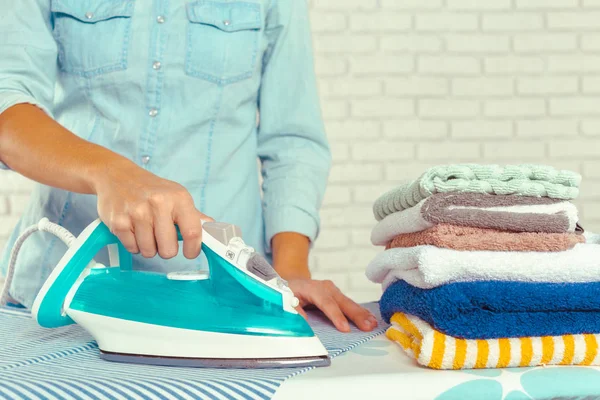 Ütü masasında giysileri ütüleyen bir kadın.