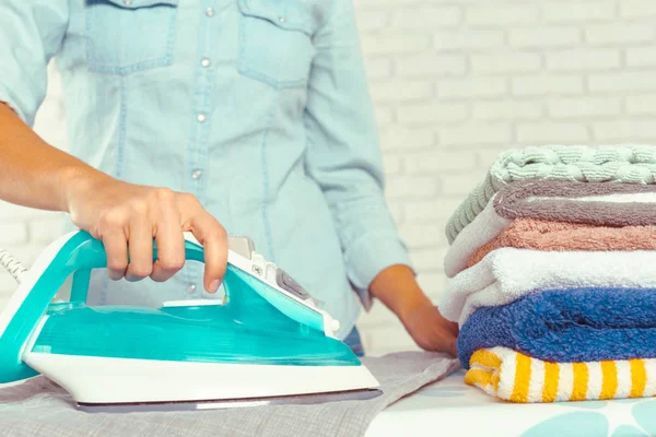 Ütü masasında giysileri ütüleyen bir kadın.