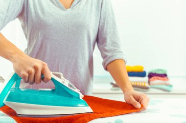 Ütü masasında giysileri ütüleyen bir kadın.