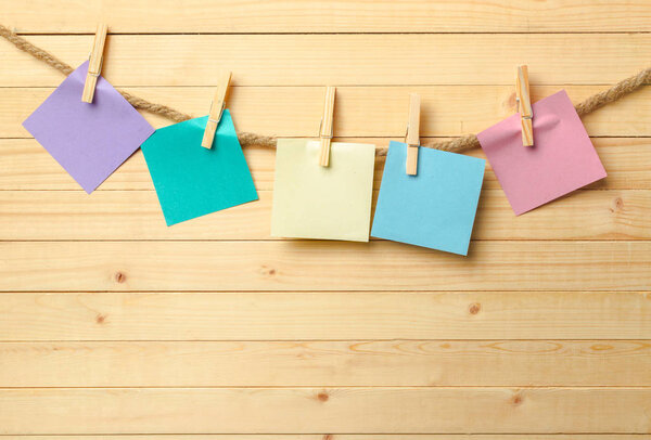 clothespins hanging with blanks paper on wooden background