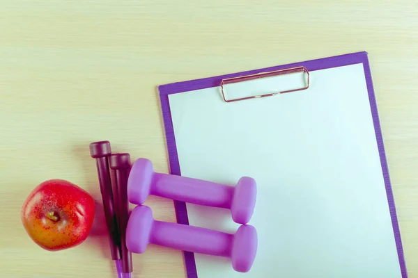 Workout plan and sports equipment on wooden desk
