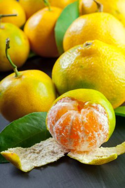 siyah arka plan üzerine yapraklarla sarı mandalina