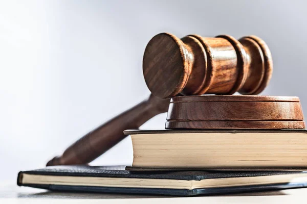 Wooden gavel and books on light background