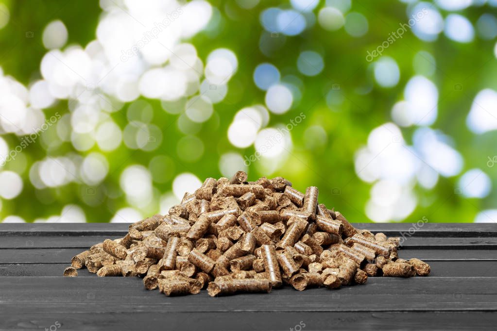 Wood pellets on green natural background.