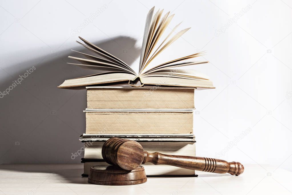 Wooden gavel and books on light background 