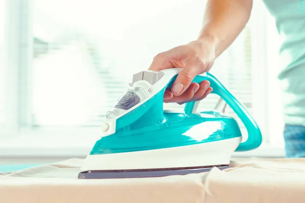 Woman's hand using steam iron ironing cloth fabric on ironing board. Small  home electrical appliances people doing housework laundry chores Stock  Photo - Alamy